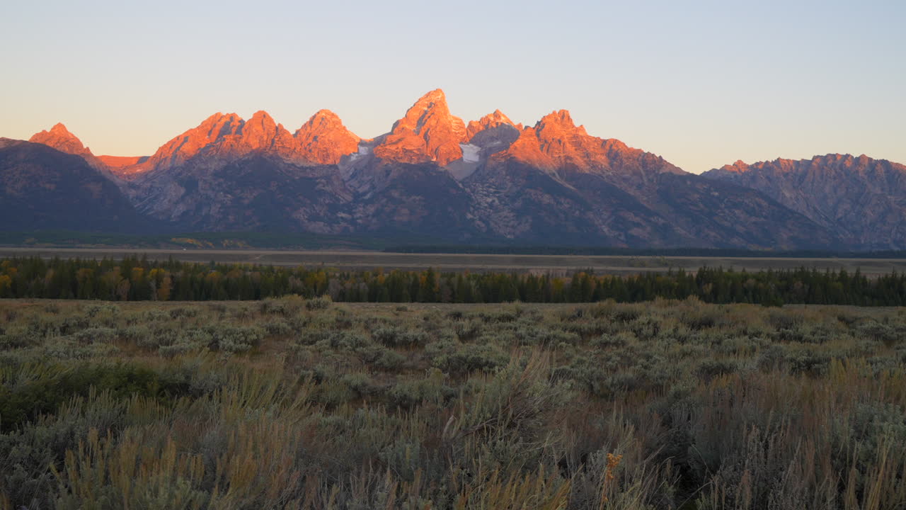 parque nacional grand teton primera luz de la mañana amanecer puesta de sol pink picos rojos jackson agujero wyoming sauce alce rancho apartamentos fotógrafo sueño hermoso deslizador cinematográfico izquierda movimiento