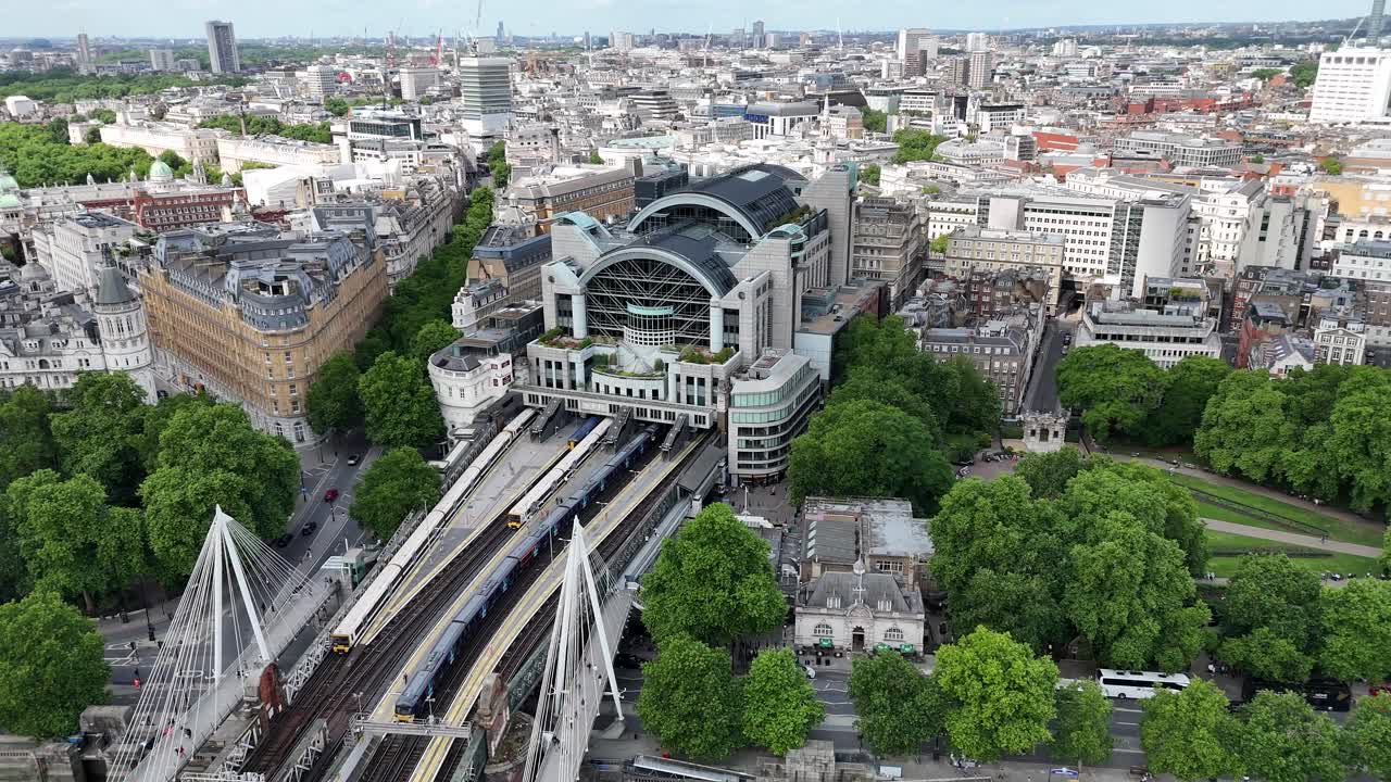 Aerial pan of Charing Cross Station, Victoria Embankment Gardens, and bustling London cityscape. Iconic landmarks and vibrant urban life capture the capital's energy.