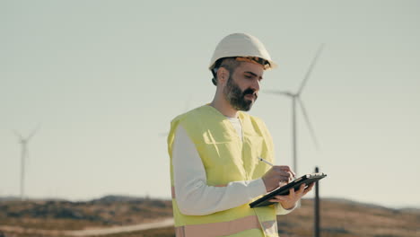 a focused caucasian male engineer in a reflective vest uses cutting-edge technology to ensure the efficiency of wind turbines, promoting clean energy production