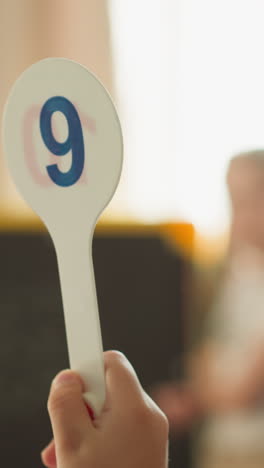 schoolchild raises plastic tag with digit nine and girl solves tasks on blackboard at home. little children study mathematics problems in classroom