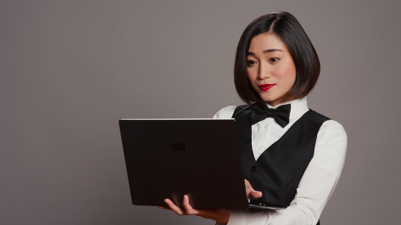 アジアのホテルの従業員がレセプションデスクでラップトップを使って人々を登録している