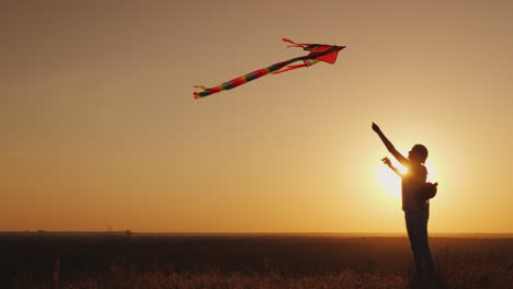 woman with a children's backpack behind her back runs a kite at sunset dream and return to childhood