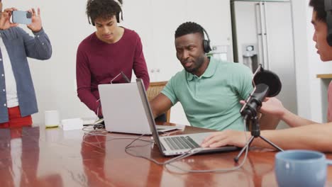 happy diverse male friends talking and recording in living room