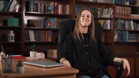 a girl is sitting in a comfortable chair, working on her laptop