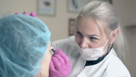 el cosmetólogo aplica tatuajes permanentes en las cejas de las niñas.