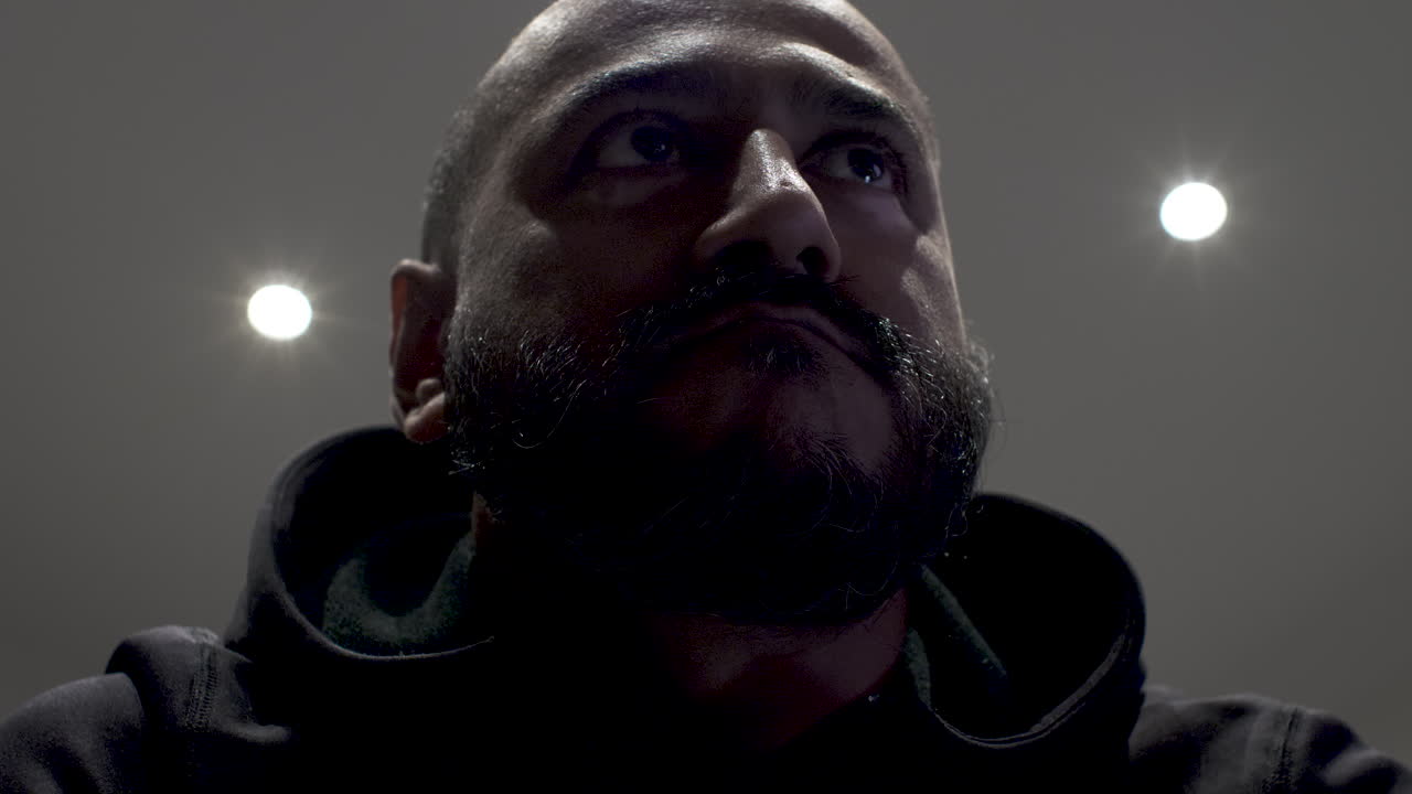 Close up shot of a man in deep thoughts anxiously looking away while sitting in a room