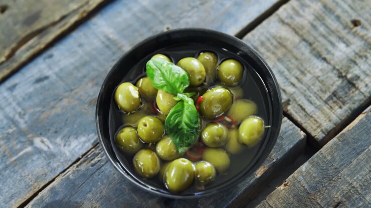 Ciotola di olive verdi all'aceto guarnite con erbe aromatiche