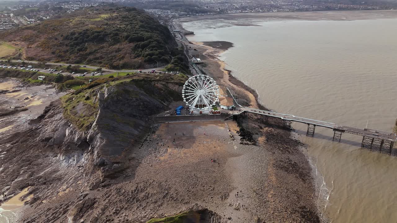 Aerial pull back shot of The Big Wheel at Mumbles Pier Swansea on a sunny day in United Kingdom.