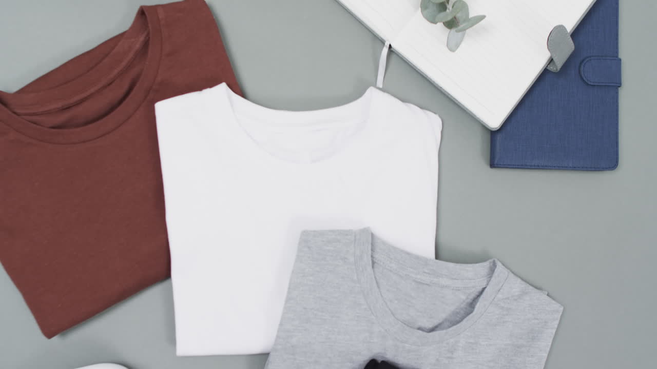 Video of flat lay of t shirts with copy space on grey background