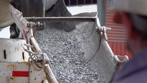un trabajador revisando la producción de cemento, bajando de una máquina mezcladora, en un sitio de construcción