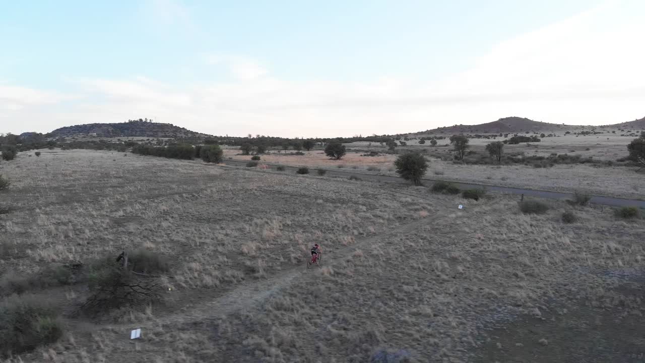 toma de pista lateral de drones de dos ciclistas de montaña en un día nublado
