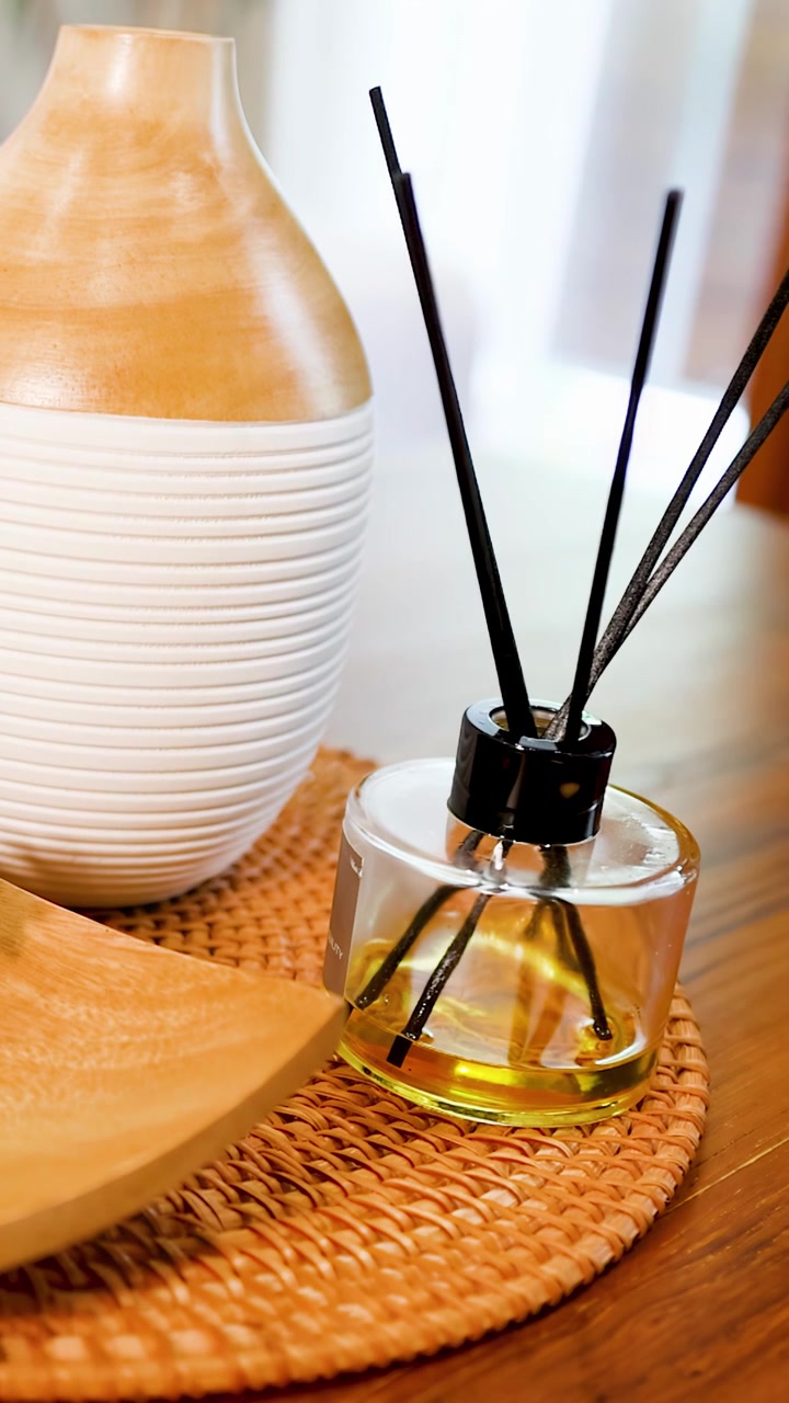 Gros plan de mains disposant un diffuseur d'aromathérapie et des pommes de pin sur une table en bois