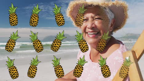 animación de piña sobre feliz mujer biracial senior tomando el sol en la playa