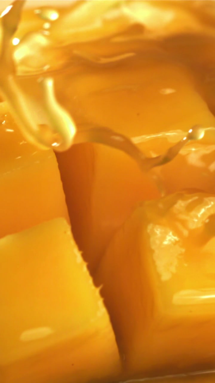Sciroppo dorato dolce versato su cubetti di mango fresco a dadini