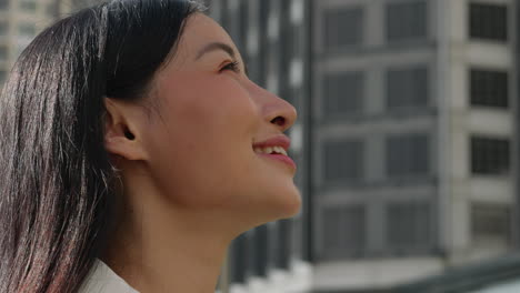 young asian woman smiling and looking up outdoors