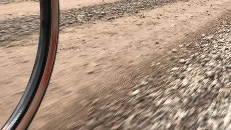 young male adult biking on a gravel road by himself on a summer day