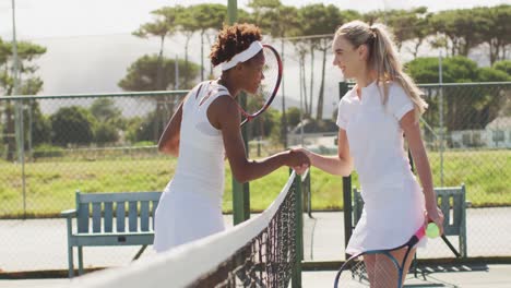 video of happy diverse female tennis players holding rackets and shaking hands