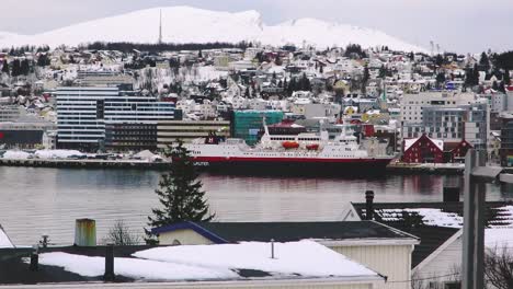 passenger ship parked at a port in a northern city with the houses covered in snow