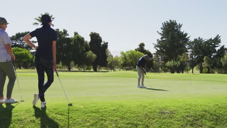 Kaukasischer-älterer-Mann,-Der-An-Einem-Strahlend-Sonnigen-Tag-Golf-Auf-Dem-Golfplatz-übt,-Während-ältere-Leute-Zuschauen