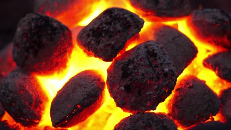 Glowing-hot-fire-briquettes-burning-in-barbeque-braai,-Close-up,-zoom-out