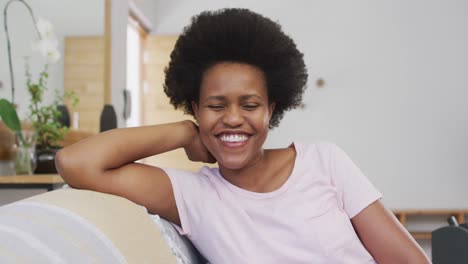 portrait of happy african american woman sitting on sofa looking at camera