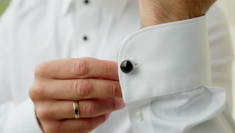 close up of hand fastening black cufflink before formal event