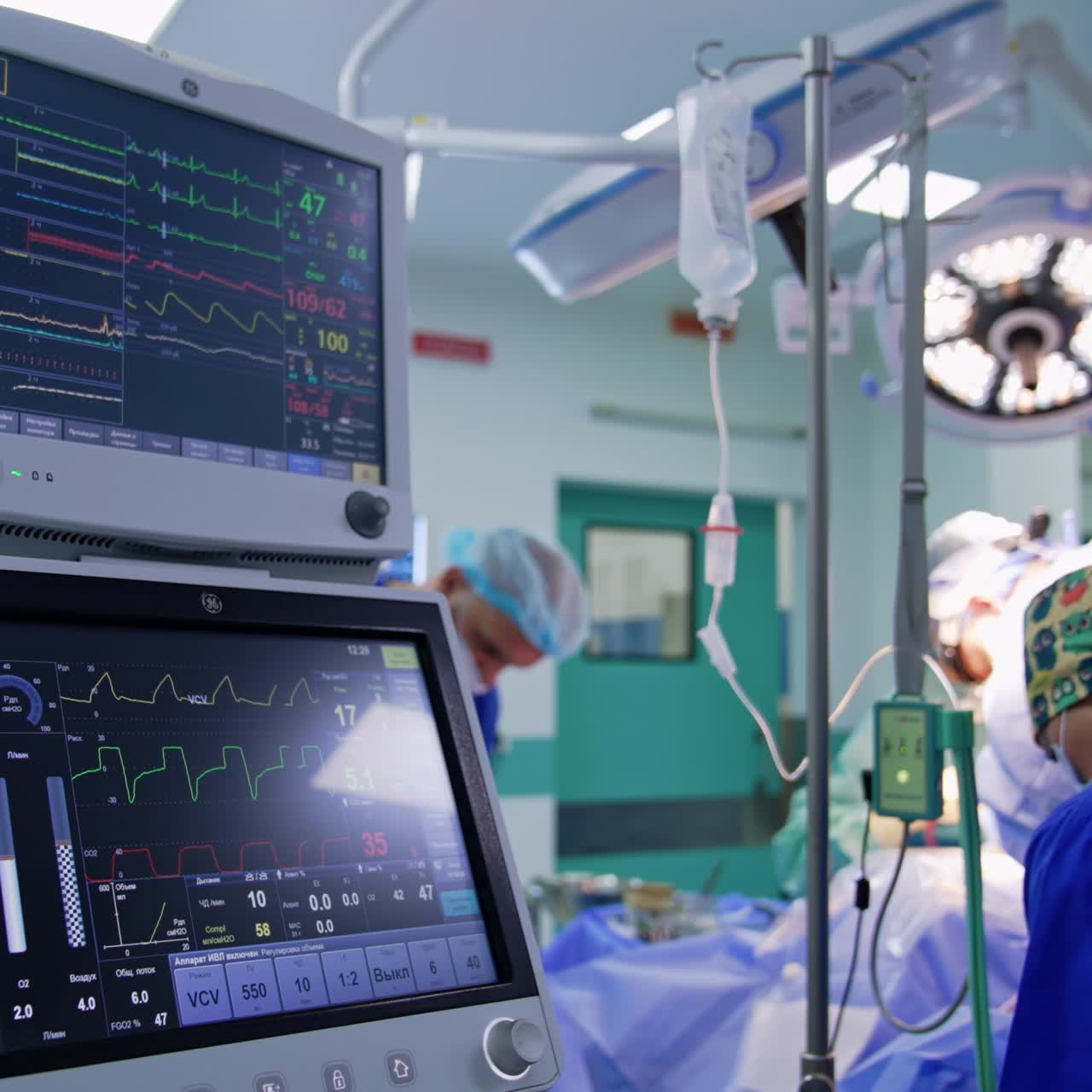 Double monitors of lung ventilator with patient's life parameters. Surgical team working at the operational table