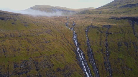 distant drone footage of cliffs with waterfalls near the saksun village on the streymoy island in the faroe islands