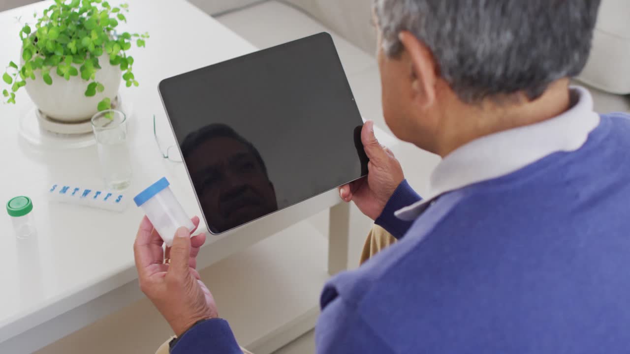 video de un hombre de dos razas con píldoras y usando una tableta en casa, copia el espacio en la pantalla