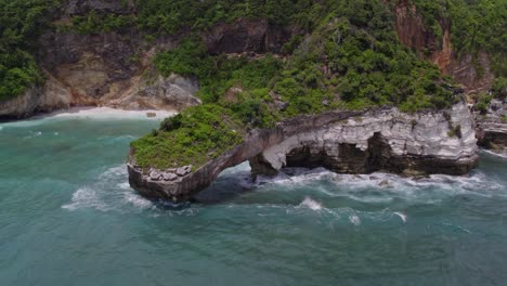 Big-lush-rock-in-clear-water-at-Mareha-Cape-at-Sumba-Indonesia,-aerial