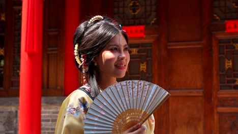 woman in traditional qing dynasty clothing holding a fan, standing in pingyao on a sunny day