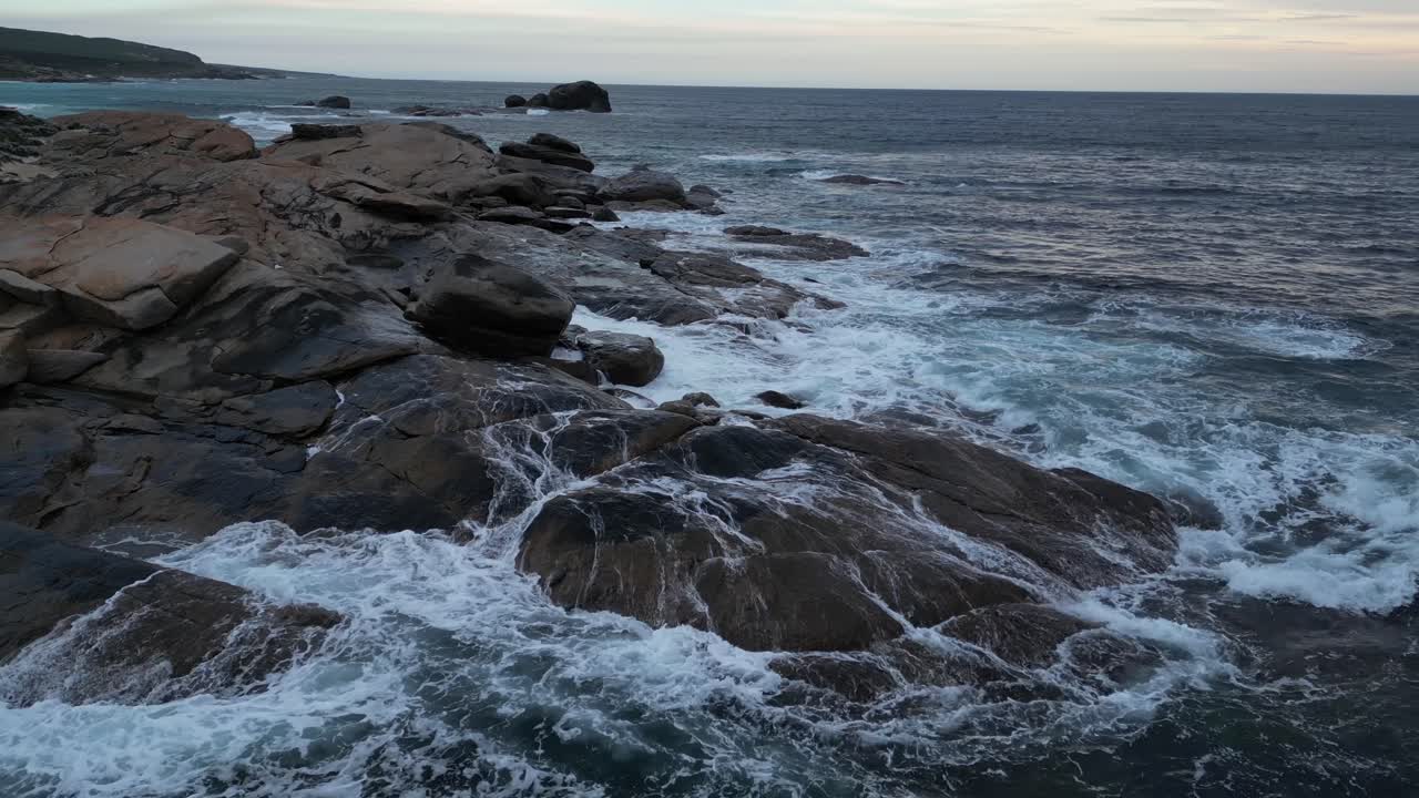 las olas del océano índico chocan contra las rocas de la playa de redgate al atardecer, australia occidental