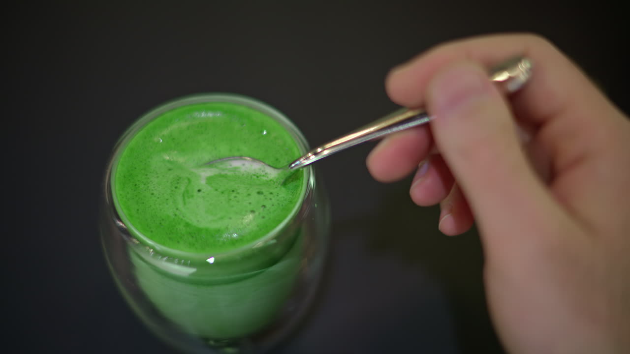 Woman stiring green matcha foam with spoon