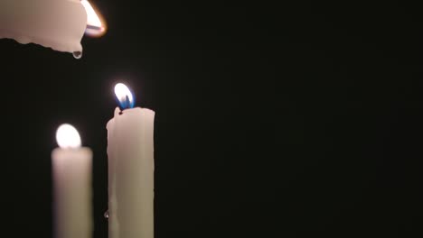 una vela blanca encendiendo una vela blanca con una vela encendida en el fondo en cámara lenta