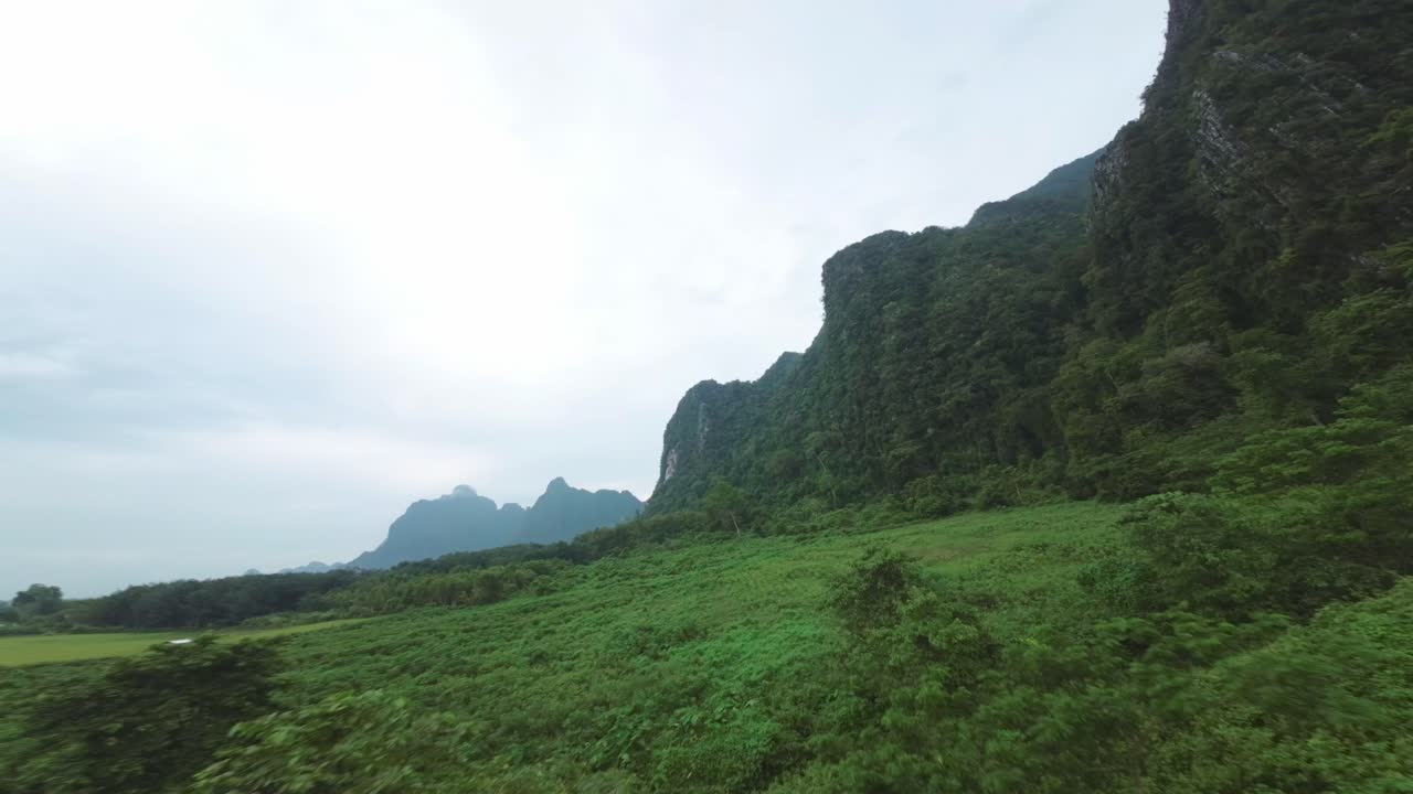 ภาพมุมสูงจากโดรนที่สวยงามของบลูลากูน ประเทศลาว มีป่าทึบและน้ำใสสะอาด ล้อมรอบด้วยหน้าผาสูงตระหง่าน โดยมีน้ำสะท้อนท้องฟ้า