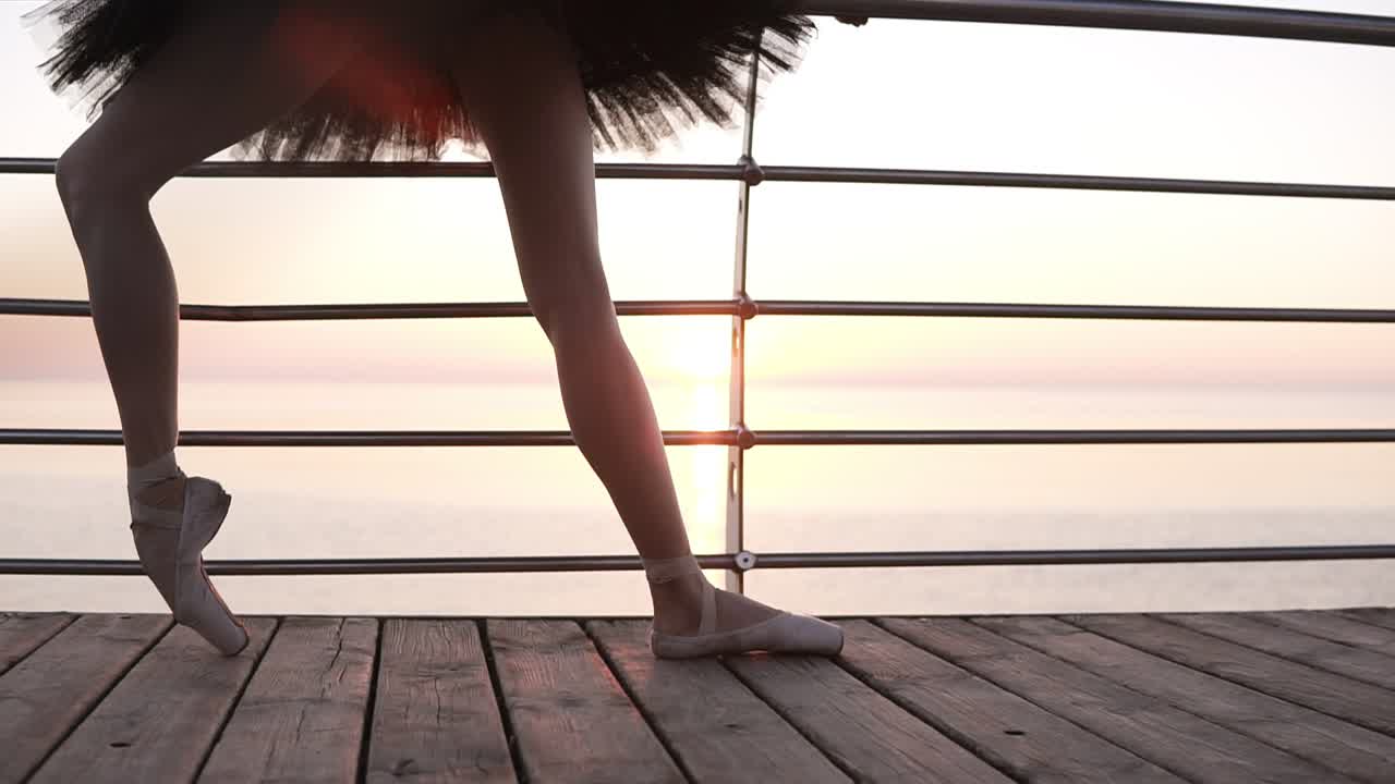 Close up of a beautiful ballerina's legs. A girl stretches her leg muscles, bending her feet. In pointe shoes. Morning on the seaside