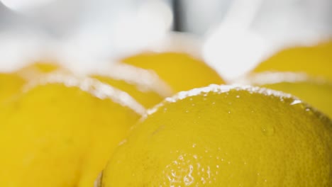 slow motion of water drops sprayed on top of lemons surface, rack focus, tracking out