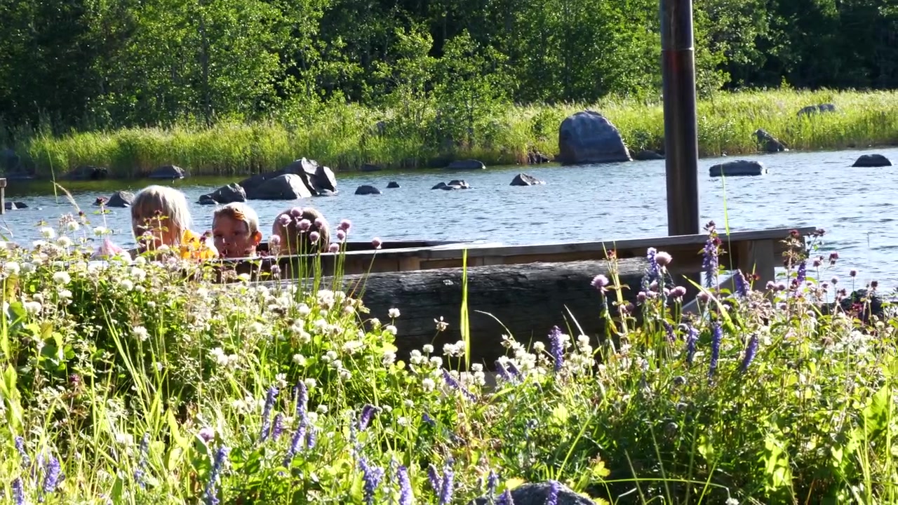 Slomo pan of happy children playing in outdoor bath by sunny lake