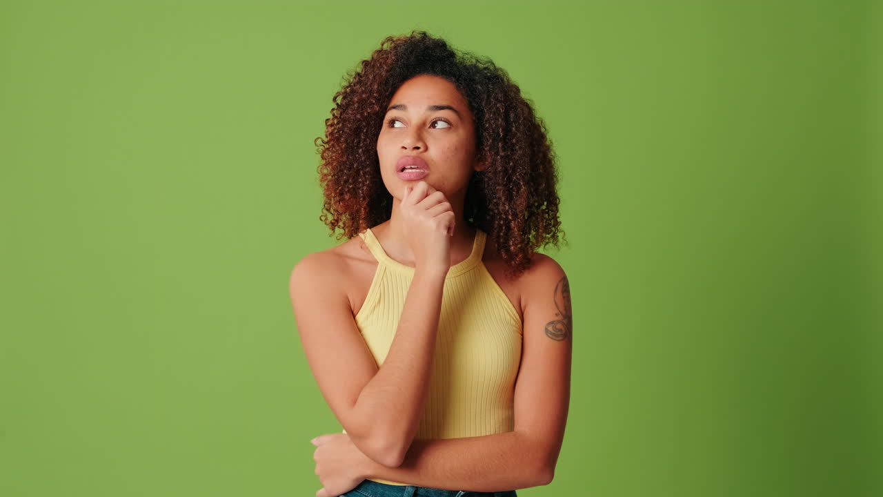 Thoughtful Young African American Woman Pondering on Green Background