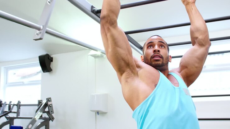 Muscular young man exercising on monkey bars at a gym