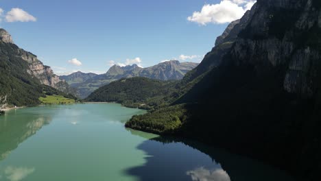 Landschaft-Eines-Majestätischen-Bergsees,-Umgeben-Von-Einem-Unglaublichen-Wald,-Aus-Der-Vogelperspektive-Gesehen,-Unberührte-Naturschönheit,-Felsige-Berge,-Die-Eine-Außergewöhnliche-Kulisse-Bieten,-Wolkenreflexionen