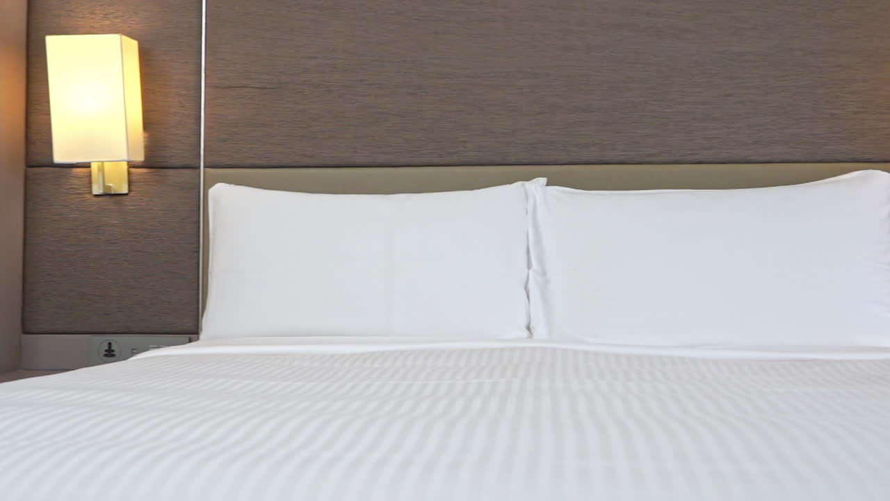 панорама справа на заправленную кровать с белым полосатым бельем и подушками-свинками в отеле-курорте в майами, штат флорида