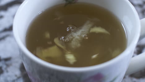 close up view of swirling ginger and lemon pieces in honey hot drink