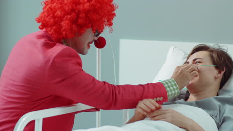 funny clown entertaining cheerful woman in hospital ward