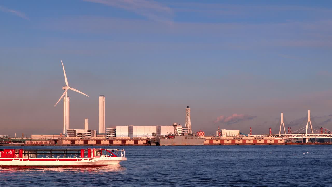 Windmill operating during sunset by the sea.