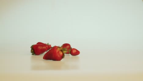 Tasty-big-ripe-strawberries-drop-on-the-table-and-rolling-off-the-screen,-delicious-heathy-vitamins-organic-fruits,-stationary-close-up-shot