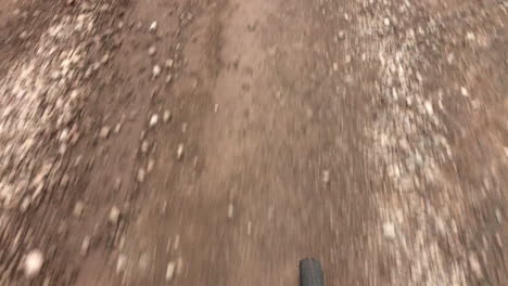 young male adult biking on a gravel road by himself on a summer day