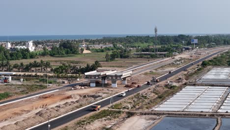 An aerial view of a vast salt pan and a highway running parallel to it. reveals the contrast between the geometric salt beds and the curving road, highlighting industrial scale and infrastructure