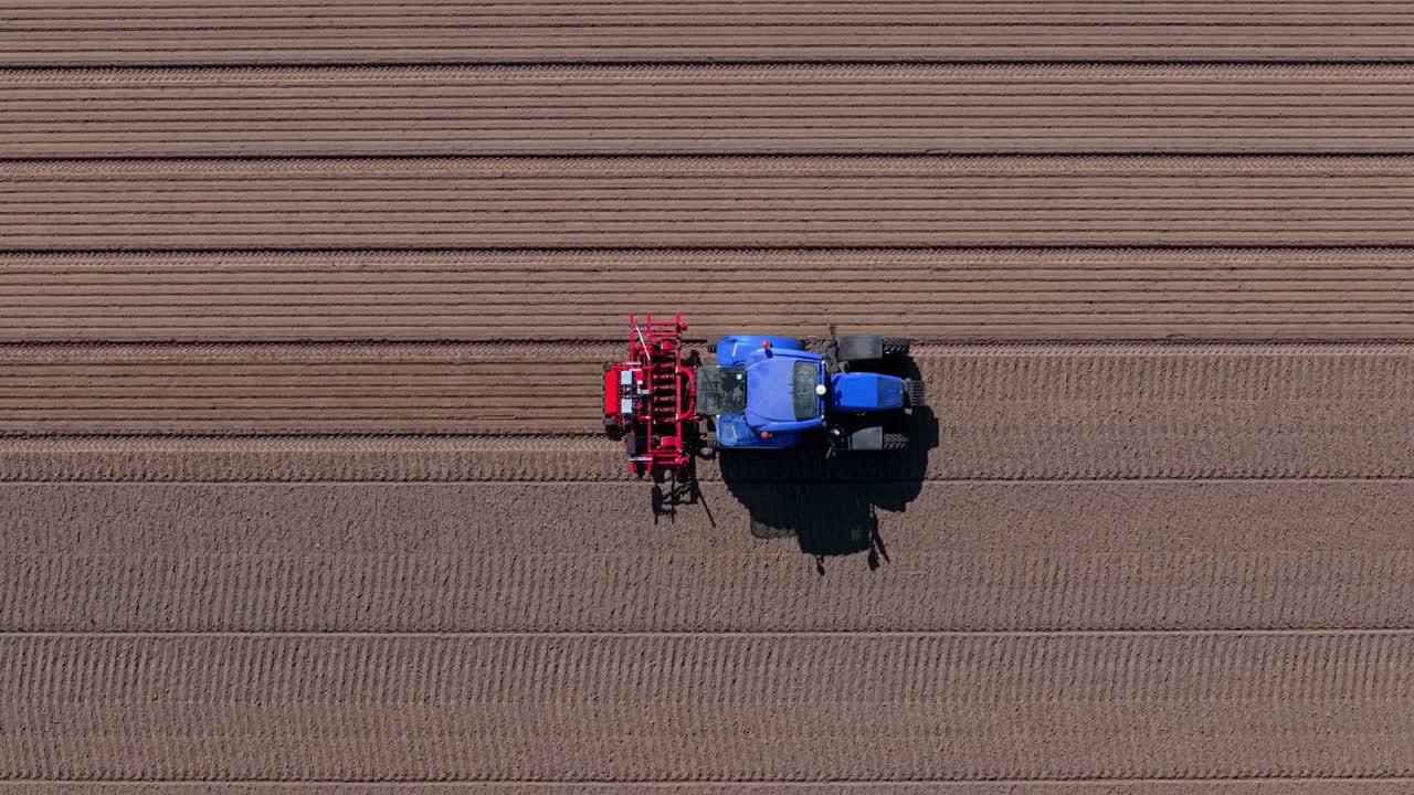 Veduta aerea di un ampio campo e di un trattore intento alla semina stagionale, Olanda.