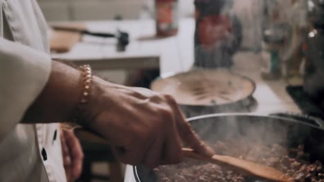caucasian male chef with unshaven face and unkept brunette hair cooks ground beef in skillet in kitchen, slow motion
